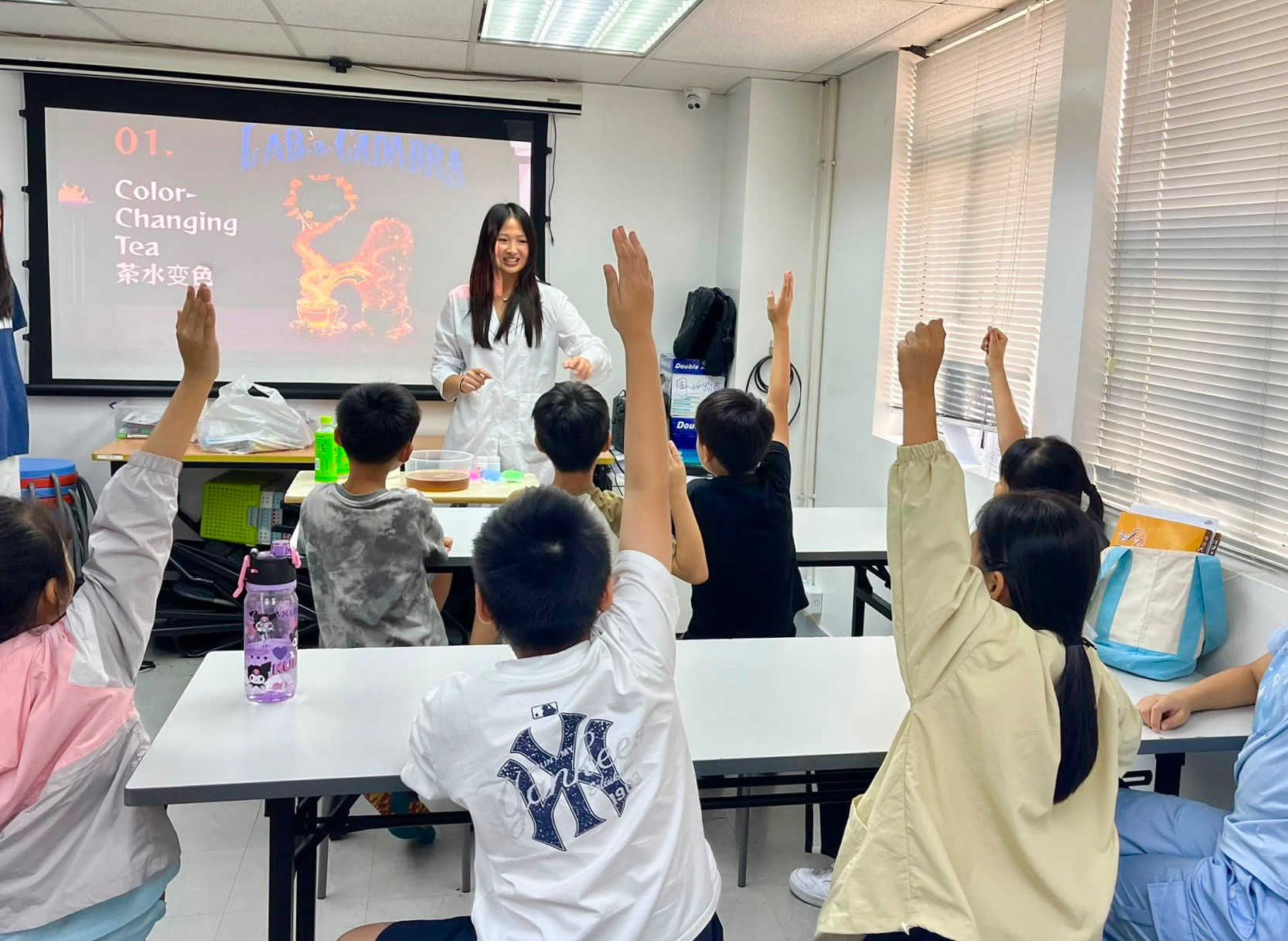 Sonia Shum leads a Lab-a-cadabra color-changing tea lesson as children raise their hands.