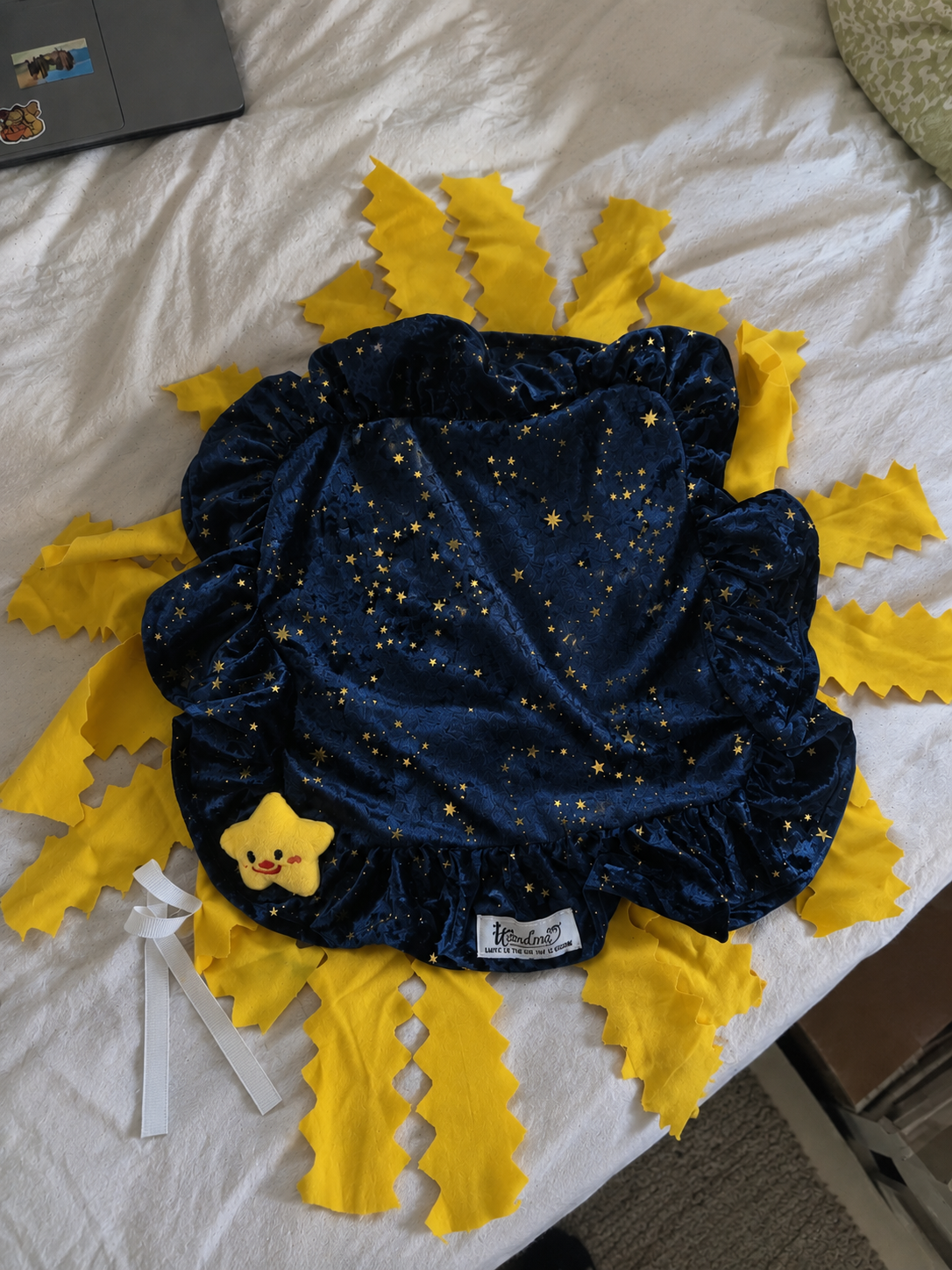 The handmade navy Cosmic Cloth laid out with its smiling star and bright yellow fabric rays.